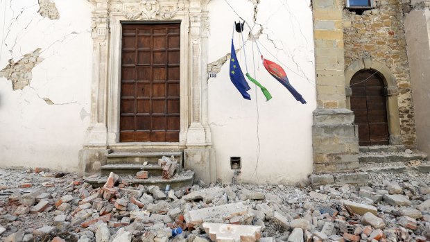 Rubble surrounds a building as a European Union flag hangs following an earthquake in Amatrice, Italy.