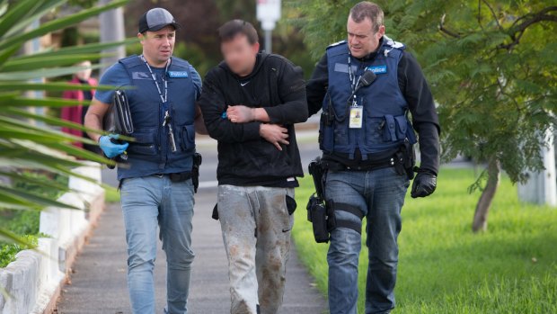 Police lead a man arrested in St Albans to a house in Essendon where further searches were carried out.