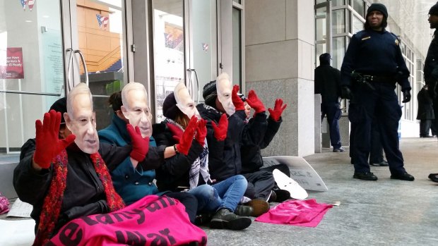 Demonstrators wear masks bearing the likeness of Israeli Prime Minister Benjamin Netanyahu and hold up "bloody" hands  outside the Washington Convention Center, which is hosting the American Israel Public Affairs Committee (AIPAC) annual policy conference.