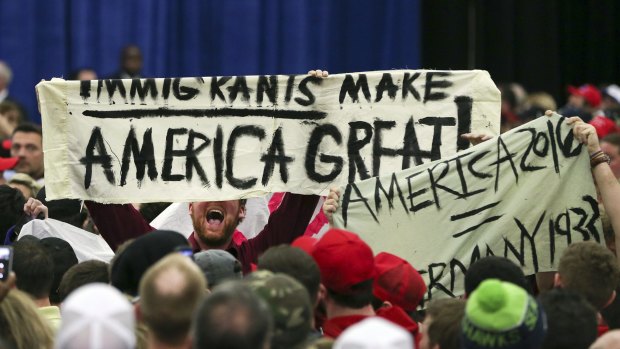 A protester holds up a sign as he disrupts a rally for Republican presidential candidate Donald Trump.