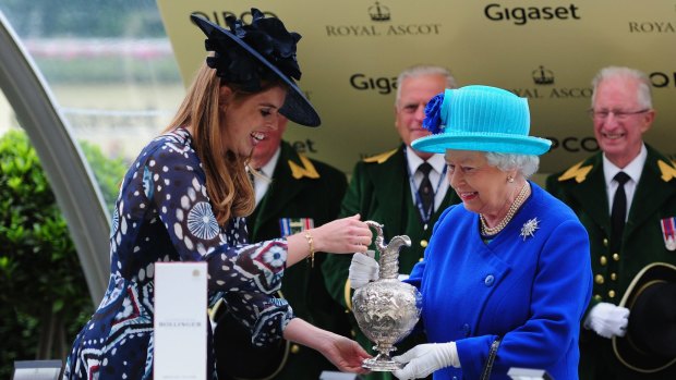 Royal day at Royal Ascot: Queen Elizabeth II smiles as she is presented the Hardwicke Stakes trophy by Princess Beatrice after her owned horse Dartmouth wins at Ascot Racecourse.