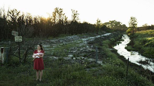 Samantha Kelly holds her baby William beside one of the drains running from the Williamtown RAAF base near Newcastle.