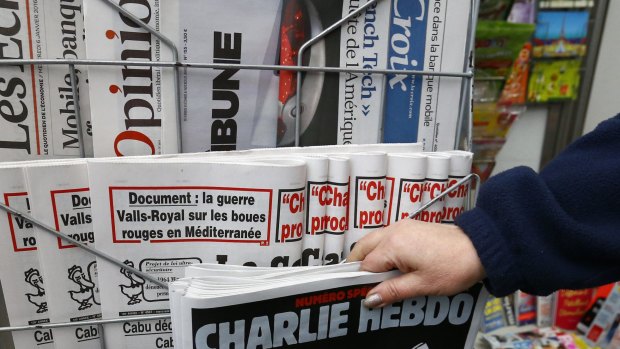 A woman picks up the issue of Charlie Hebdo that marks one year after the attacks on the French satirical newspaper.