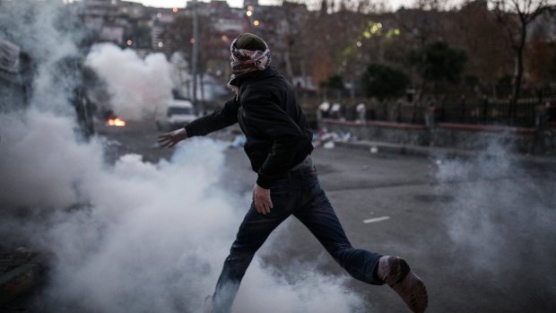 A masked man throws a petrol bomb toward police using water cannon and teargas to disperse people protesting against security operations against Kurdish rebels in southeastern Turkey, in Istanbul.