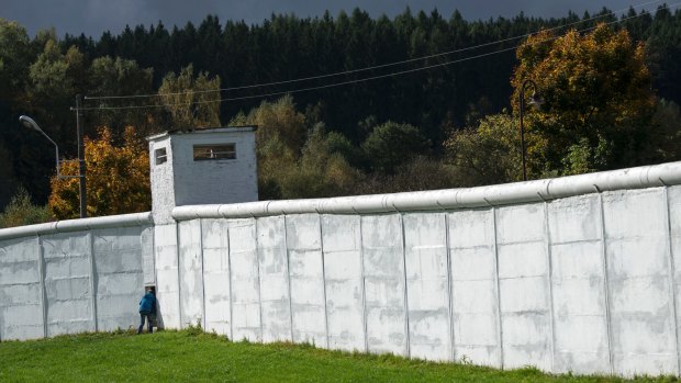 A visitor looks through a small gate in the former GDR border wall in Moedlareuth, Germany.