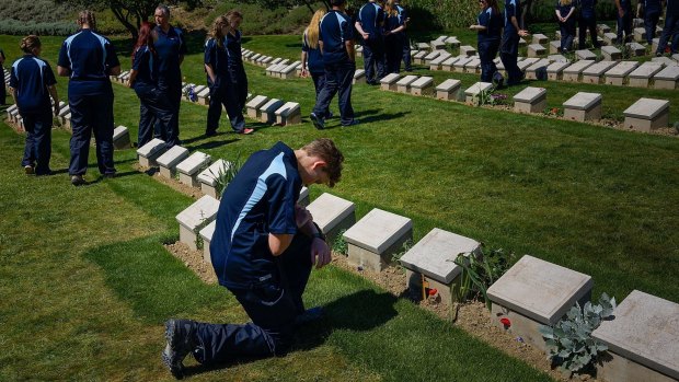 A NSW student on the schools tour of Gallipoli kneels in front a grave stone at Shrapnel Valley Cemetery. 
