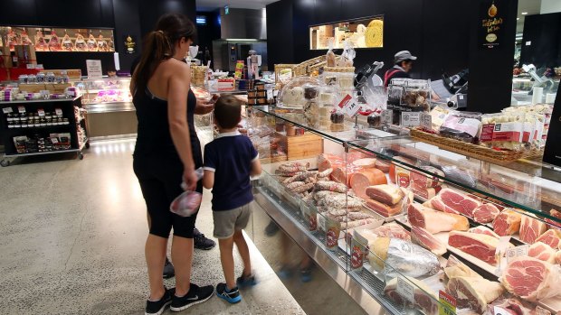 Customers purchase items from the deli counter at an IGA supermarket.