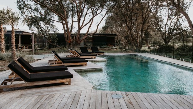 Prepare to be wowed by the pool area at the end of this walkway with its wooden deck, clear fencing, clean lawns, sun lounges and a cane swing seat.