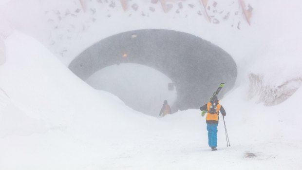 Snow drifting around the tunnel at Hotham as people hike up the closed road to ski.