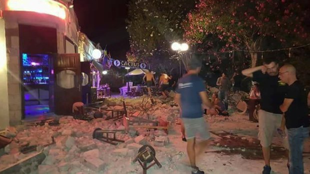 A man lies on the ground as other tourists stand outside a bar after an earthquake on the Greek island of Kos early on Friday.