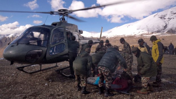 An injured survivor of a snow storm is assisted by army personel into a Nepalese Army helicopter.