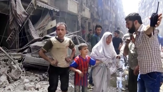 A man leads a woman and child to safety after air strikes hit Aleppo.