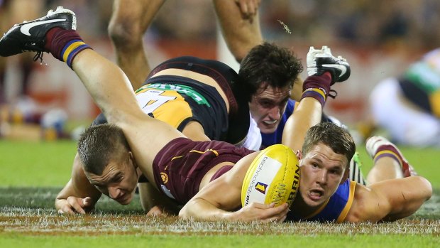 The Lions' Jack Redden is tackled by Dustin Martin in the Tigers' win at the Gabba on Sunday. 