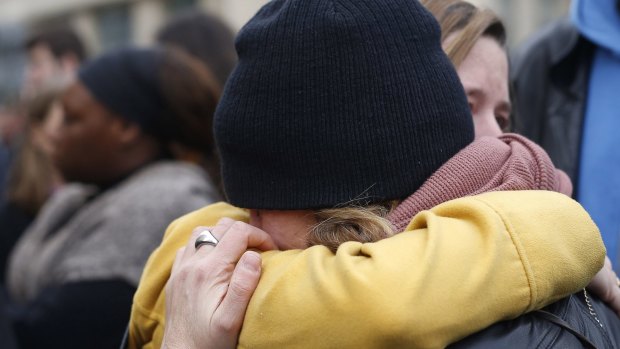 People hug in the street in front  of the Carillon cafe and the Petit Cambodge restaurant in Paris on Saturday.