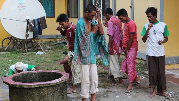 Migrants brush their teeth and clean up at the temporary shelter in Lhoksukon.