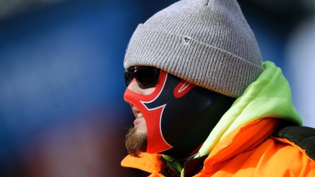 A fan is bundled against the cold weather as he watches teams warm up before an NFL football game in Massachussets.
