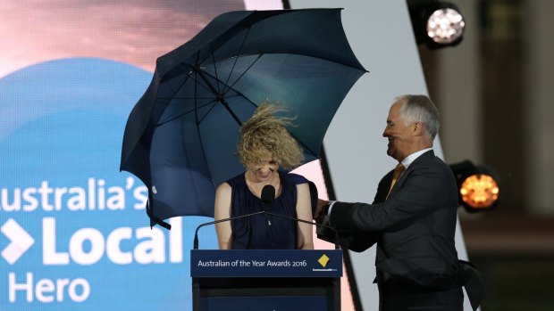 Local Hero of the Year Catherine Keenan is shielded by Prime Minister Malcolm Turnbull at a windy Parliament House.