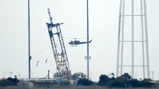 A helicopter flies over the damaged launch pad at NASA's Wallops Flight Facility in Virginia after the Antares rocket failure on Wednesday.