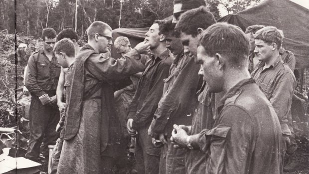 Members of 102nd Field Battery, Royal Australian Artillery, and 1st Battalion, The Royal Australian Regiment, receive communion, Phuoc Tuy Province, South Vietnam, 1968. 
