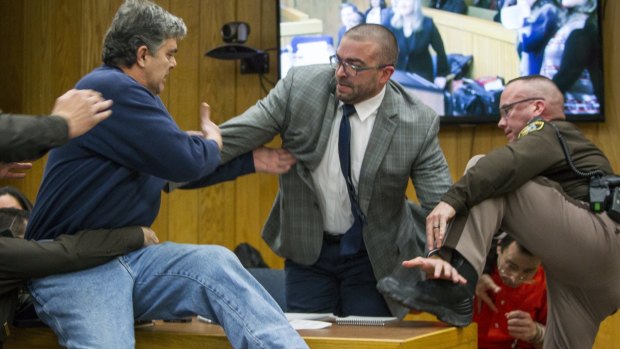 Randall Margraves, father of three victims of Larry Nassar, lunges at the disgraced doctor (bottom right) during a sentencing hearing. 