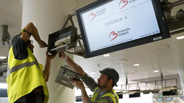 Workers repair a screen in the departures hall at Zaventem Airport in Brussels.