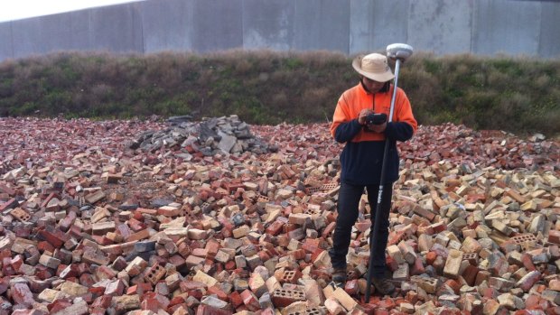 A clean-up worker amid waste illegally dumped at a field in Prima Court, Tullamarine, by demolition company Monark Industries, trading as Hughes Demolition. 