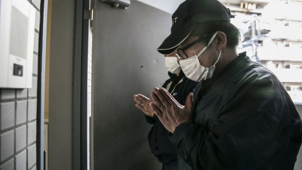 Yautaka Kimura, left, and Akira Fujita pray after cleaning an apartment in Kawasaki, Japan, where a man had died about four months before his body was discovered. So-called "lonely deaths" happen frequently in Japan.