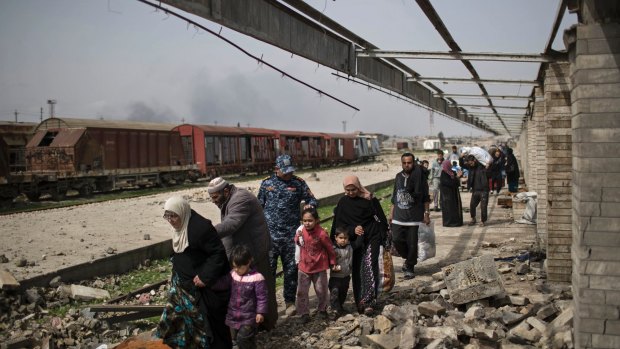 Iraqi civilians flee through a destroyed train station during fighting between Iraqi security forces and Islamic State militants.