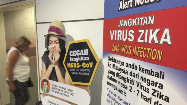 A traveller walks past a travel advisory on the Zika virus infection in Kuala Lumpur International Airport.