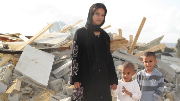 Rifa al-Oqbi and her sons stand in front of their demolished home in the Bedouin village of al-Qrain in November 2011.