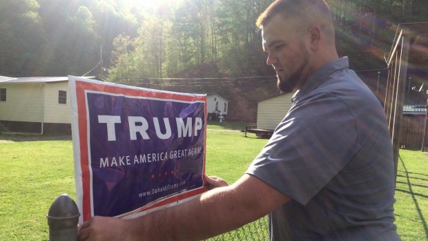 Billy Prater, from a family of diehard Democrats, adjusts a Donald Trump sign on his fence in West Virginia in April. Laid off from the mines, he had been out of work for more than a year.  