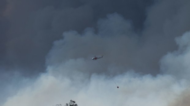Strong winds fan bushfires:
 A water bombing helicopter at work over the fire.