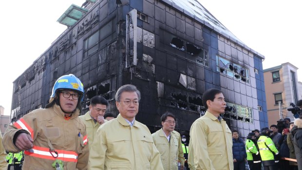 South Korean President Moon Jae-in, second from left, visits the site of a burnt out building after a fire in Jecheon.