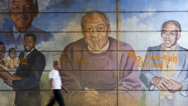 A man walks past a mural depicting entertainer Bill Cosby, centre, in Philadelphia, which has been painted over as new details emerged of his testimony in a sexual-assault lawsuit.