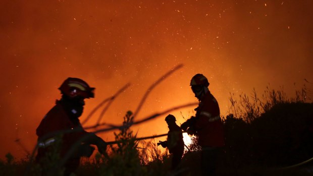 Firefighters battle a wildfire raging near houses on the outskirts of Obidos, Portugal, in the early hours of Monday.