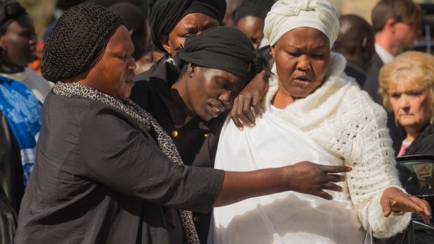 Akon Guode (centre), the mother of three children killed in a lake in Wyndham Vale, makes her way from the funeral service on Saturday.