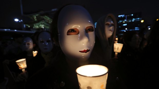 South Korean college students wearing masks hold up candles as they march after a rally calling for South Korean President Park Geun-hye to step down.