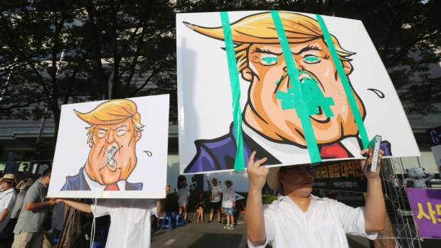 Protesters against the US hold up defaced images of Donald Trump during a rally opposing the THAAD near the US embassy in Seoul on Saturday.