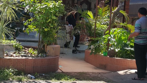Forensic officer carying pillow and bed sheet out of the Sanur villa.