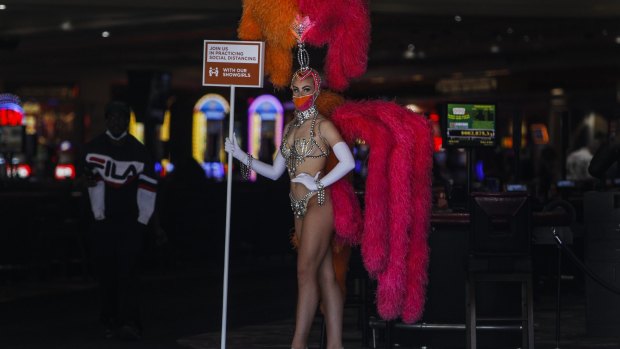 A showgirl wearing a protective mask promotes social distancing at the entrance to the Flamingo Las Vegas casino