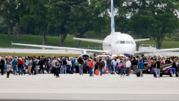 People stand on the tarmac after a shooter opened fire inside the terminal.