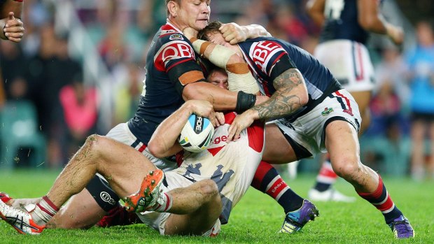 Wrestle: Jack de Belin of the Dragons is tackled by Jake Friend and Jared Waerea Hargreaves of the Roosters on Saturday.