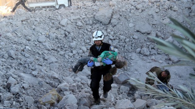 A man carries a wounded child over the wreckage of collapsed buildings after Russian forces carried out air strikes on residential areas in Yaqid al-Adas, near Aleppo.