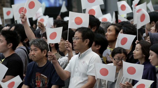 Attendees hold Japanese national flags as they wait for the arrival of Shinzo Abe during a campaign event in Tokyo.