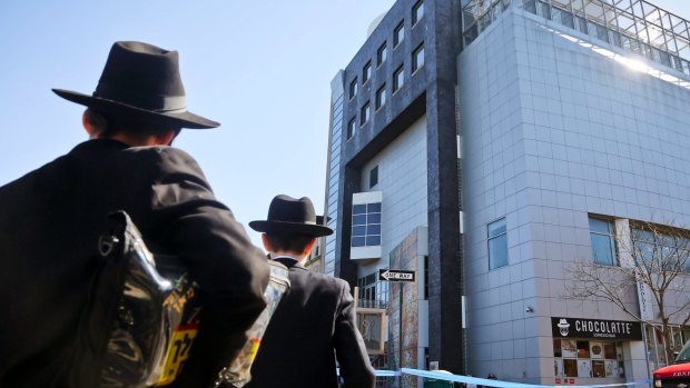 Two young men who left a nearby synagogue watch police activity outside the Jewish Children's Museumin New York following a bomb threat.