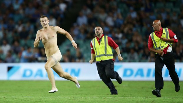Costly invasion: Security staff chase a streaker on the playing field during the round one Super Rugby match between the Waratahs and the Reds at Allianz Stadium.