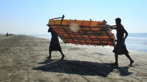 Rohingya fishermen carry a fishing raft, constructed with empty plastic containers, up the beach in Maungdaw, western Rakhine state, Myanmar. Their usual, sturdy fishing boats were outlawed three months ago.