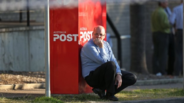 A man leans against an Australia Post letterbox at the scene of a shooting outside Warners Bay Post Office on Wednesday afternoon.
