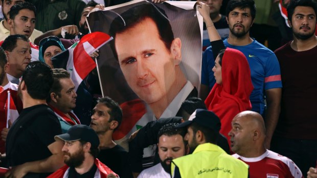 Political minefield: Syrian fans hold a portrait of President Bashar Assad, before their draw with Iran that qualified the team for the play-off.
