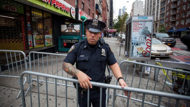 A New York City Police Department officer places barricades near the site of Saturday night's explosion in Chelsea. 